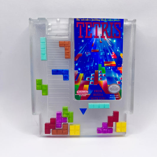 Clear resin NES cartridge art featuring vibrant 3D Tetris block embellishments for a unique retro gaming display. This handmade decorative item is a must-have for gaming enthusiasts and collectors of Nintendo memorabilia.