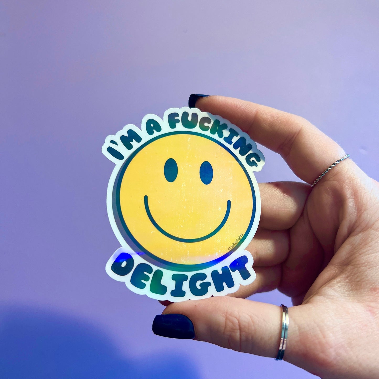 A holographic sticker featuring a smiley face with the bold text I'm a F**king Delight. Perfect for adding humor and positivity to your belongings.