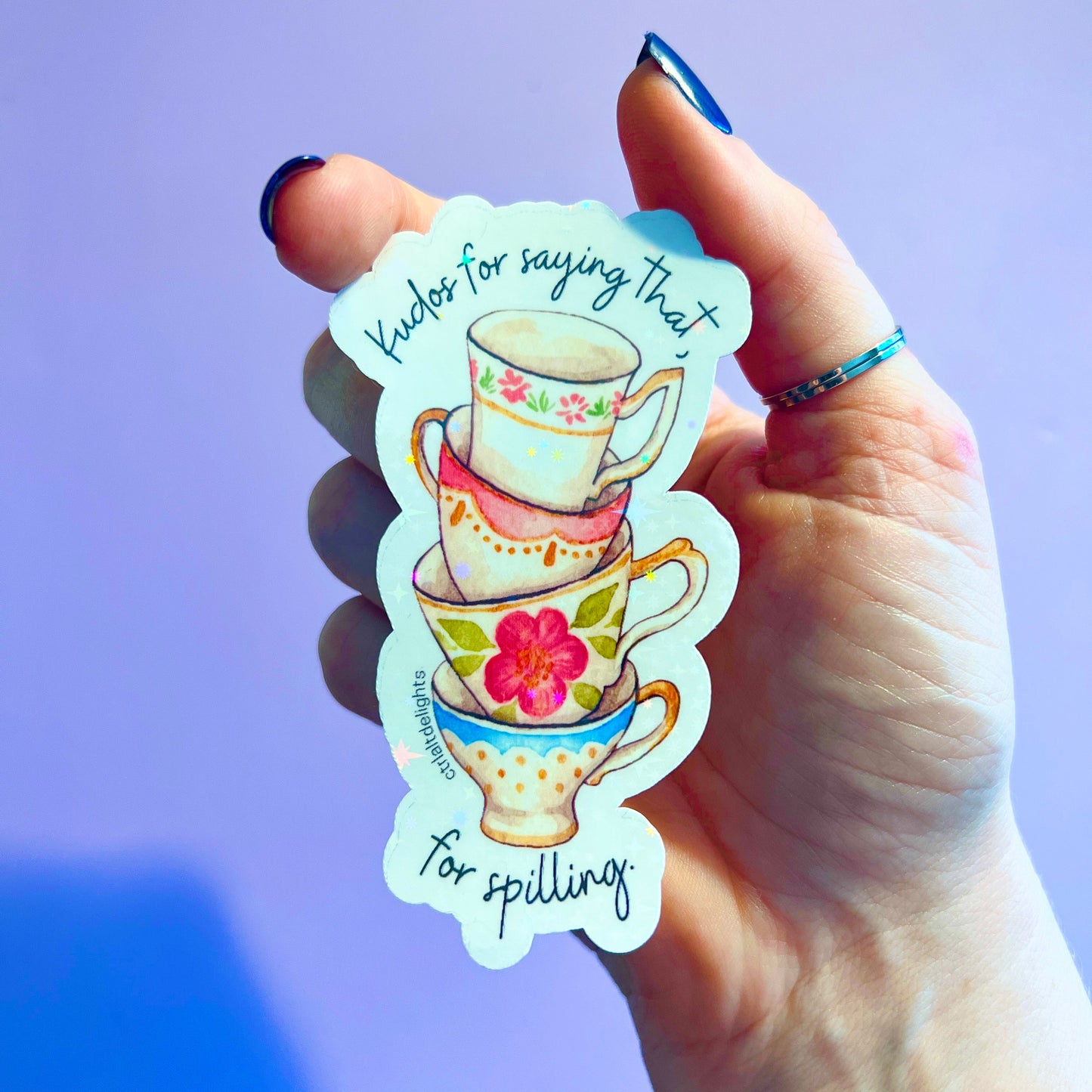 Whimsical vinyl sticker featuring a stack of colorful tea cups with the phrase Kudos for saying that. Perfect for tea lovers and those who enjoy spilling the tea. Great for decorating laptops or journals