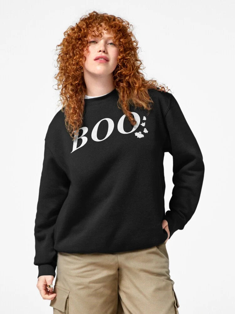 Black sweatshirt with BOO text in white and small ghost graphics, perfect for Halloween. Cozy and fun for fall, great for parties or casual wear, adding a playful touch to your spooky season outfit. Featured on a model.