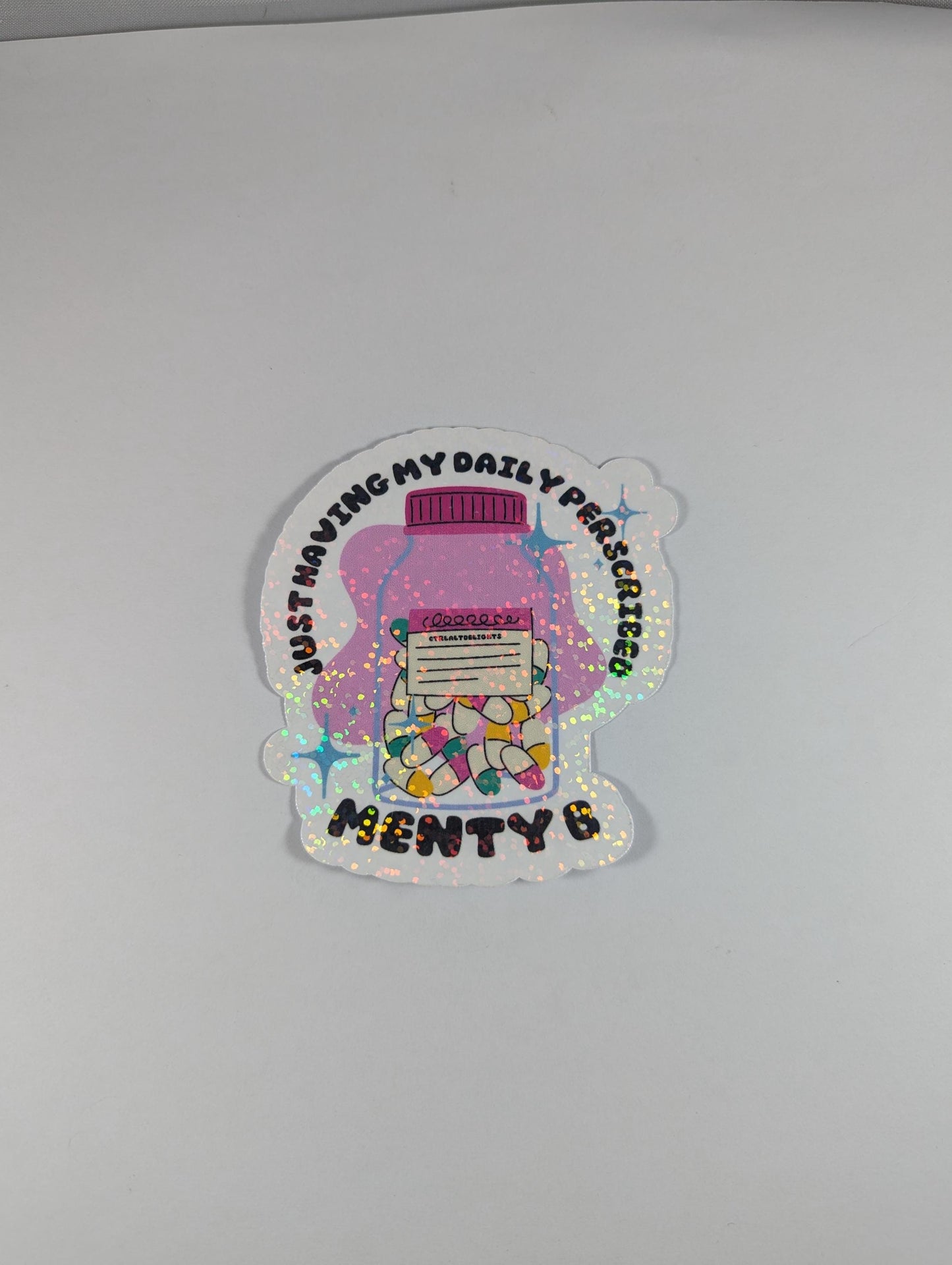 Holographic sticker featuring a prescription bottle with the words 'Just Having My Daily Prescription of Menty B.' Perfect for mental health humor and adding some fun to your laptop, water bottle, or journal.