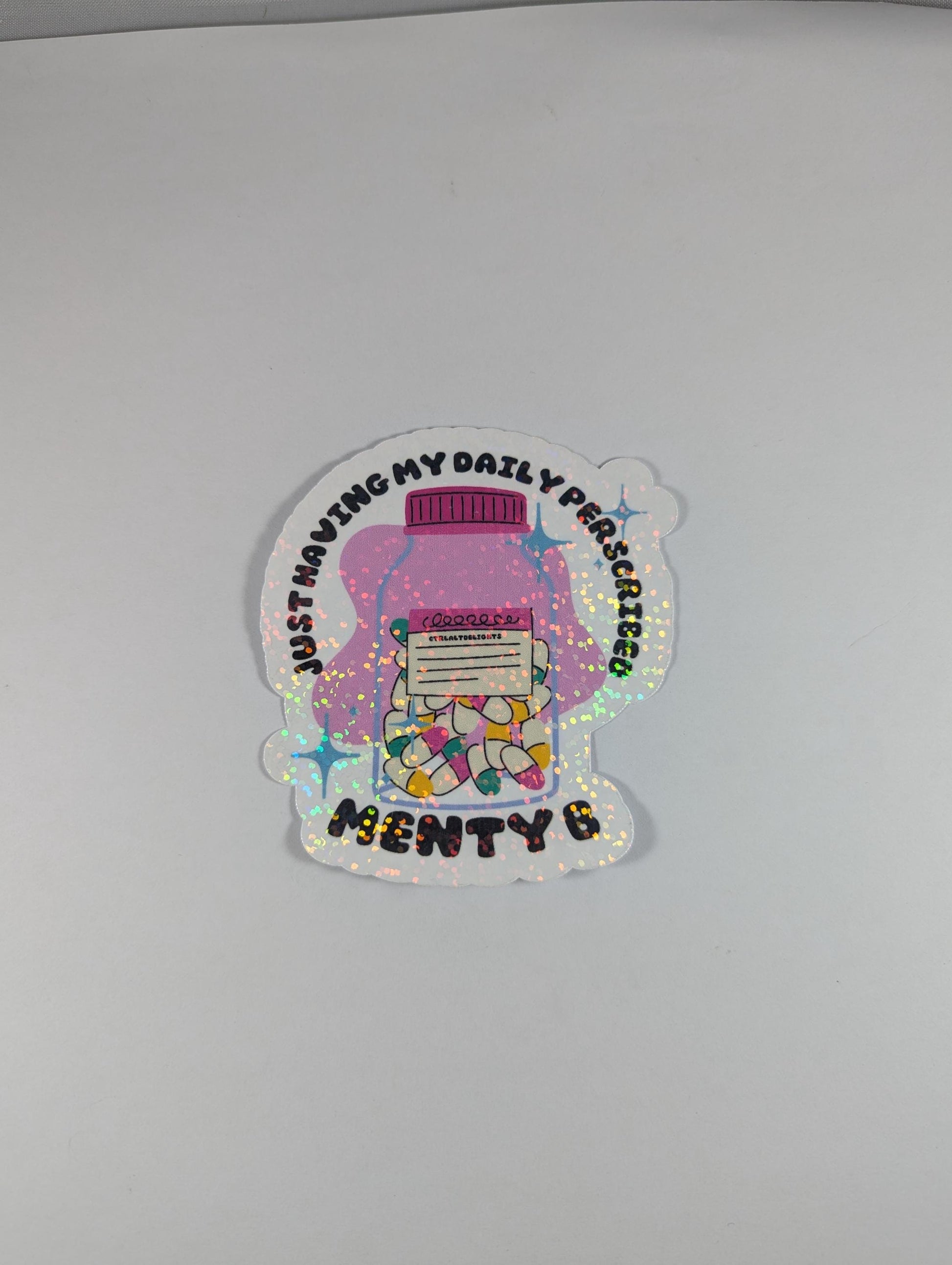 Holographic sticker featuring a prescription bottle with the words 'Just Having My Daily Prescription of Menty B.' Perfect for mental health humor and adding some fun to your laptop, water bottle, or journal.