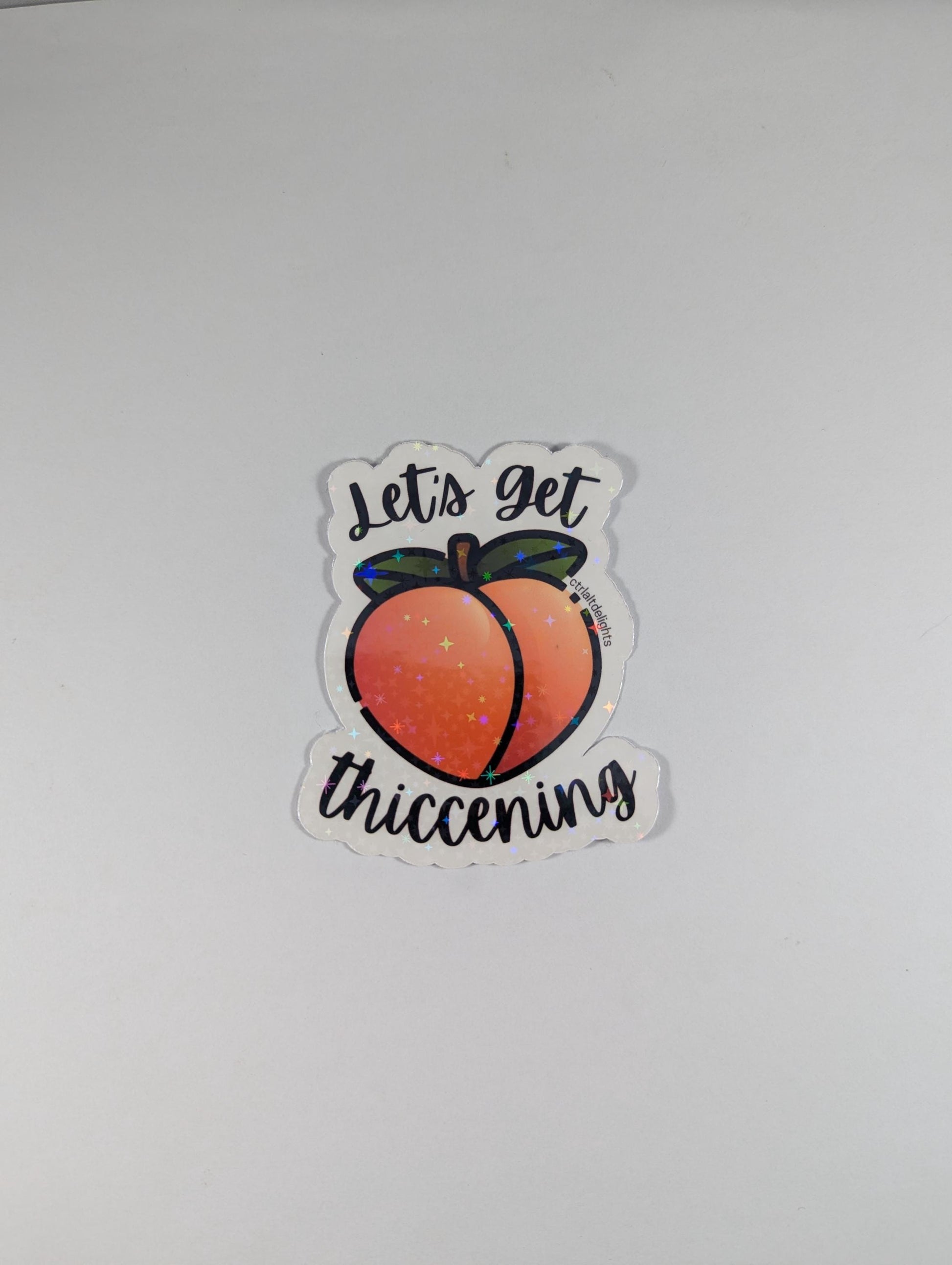 Holographic "Let's Get Thiccening" peach sticker featuring a cute peach design. Perfect for decorating water bottles, laptops, journals, or any surface that needs a fun, thicc touch.