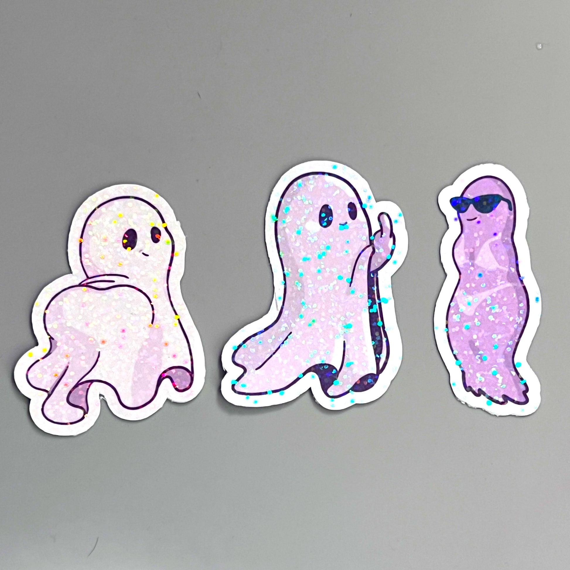 Holographic ghost sticker set featuring three adorable and sassy ghost designs. Perfect for decorating laptops, water bottles, or journals. Add a spooky yet cute touch to your accessories.