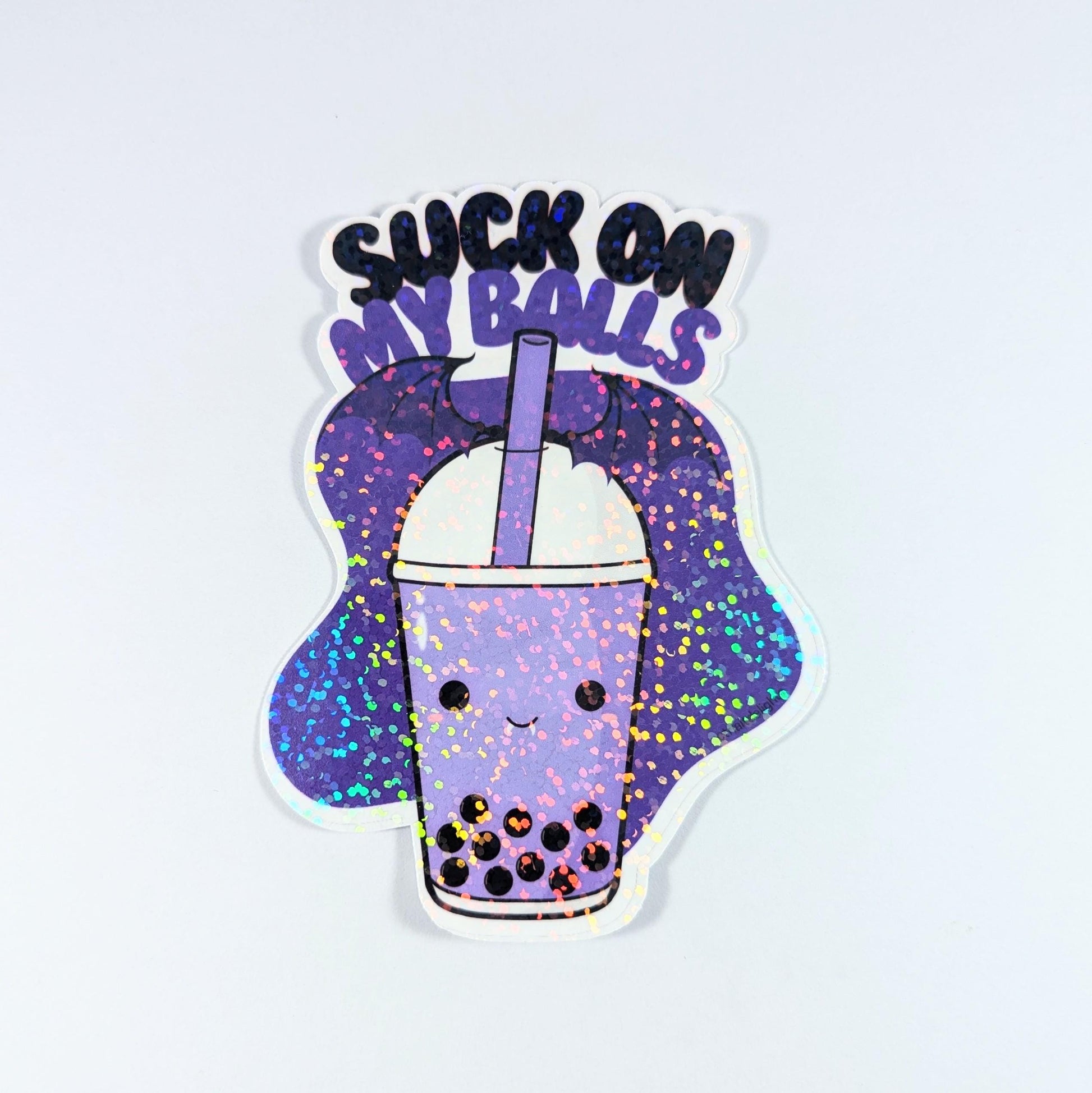 Holographic boba tea sticker with a cute bubble tea cup and the playful phrase Suck on My Balls in bold text. Perfect for decorating water bottles, laptops, and journals, this sassy and fun vinyl decal adds a quirky touch to your accessories.