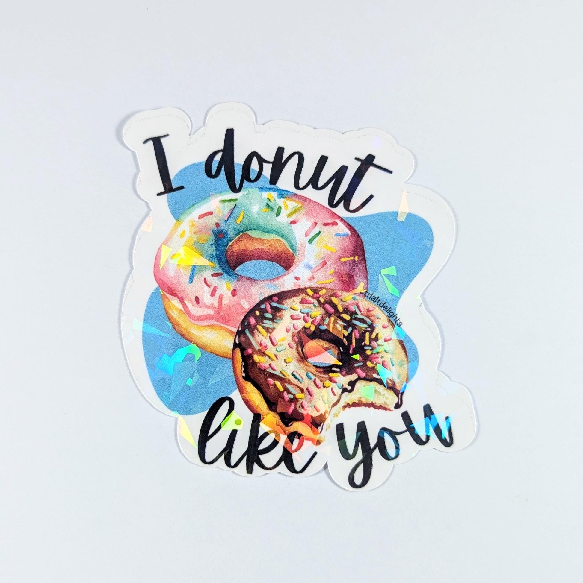 This adorable holographic donut sticker features two colorful donuts and the pun I Donut Like You. Perfect for laptops, water bottles, or journals, it makes a great gift for food lovers and pun enthusiasts.