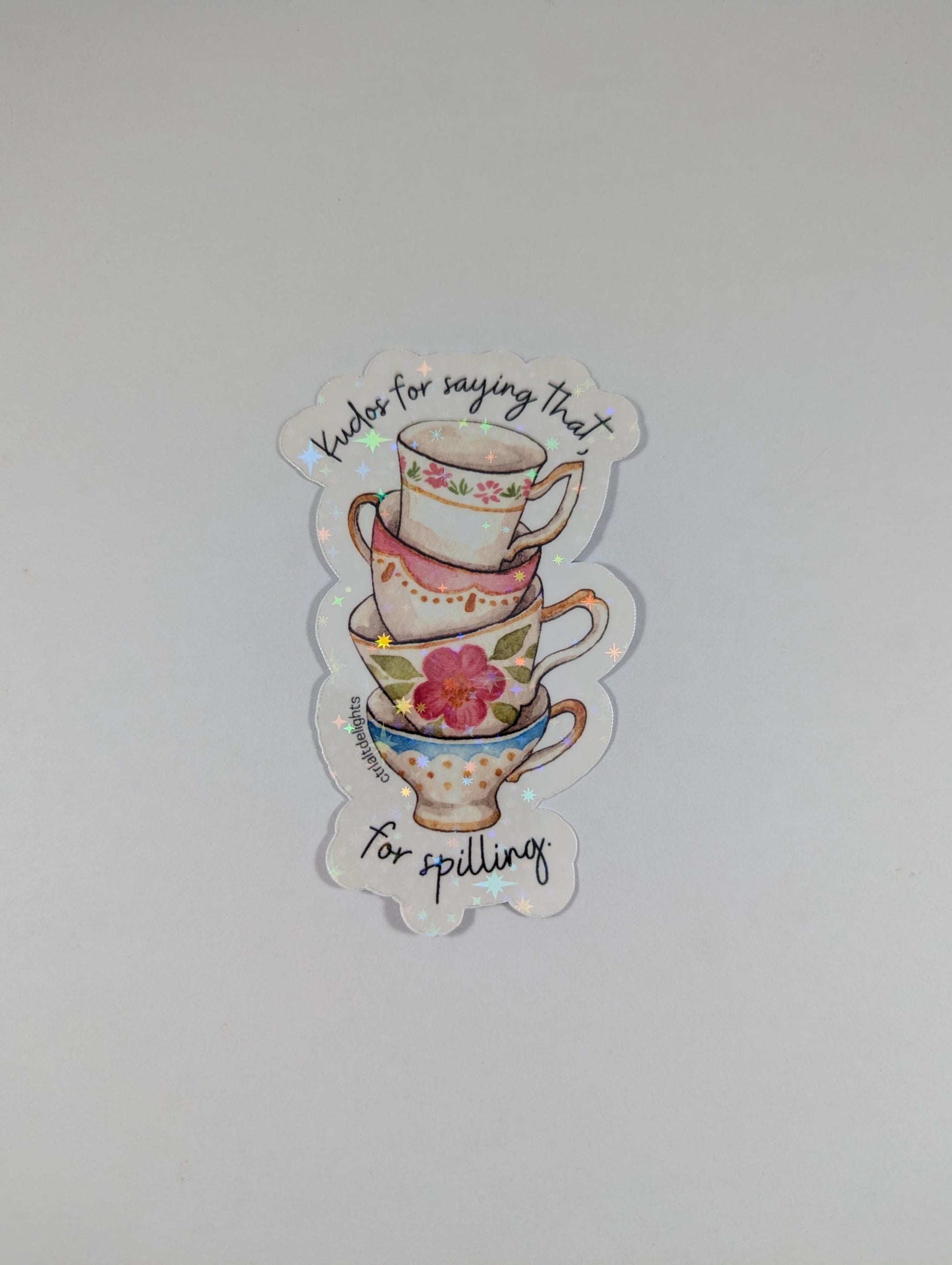 Whimsical vinyl sticker featuring a stack of colorful tea cups with the phrase Kudos for saying that. Perfect for tea lovers and those who enjoy spilling the tea. Great for decorating laptops or journals