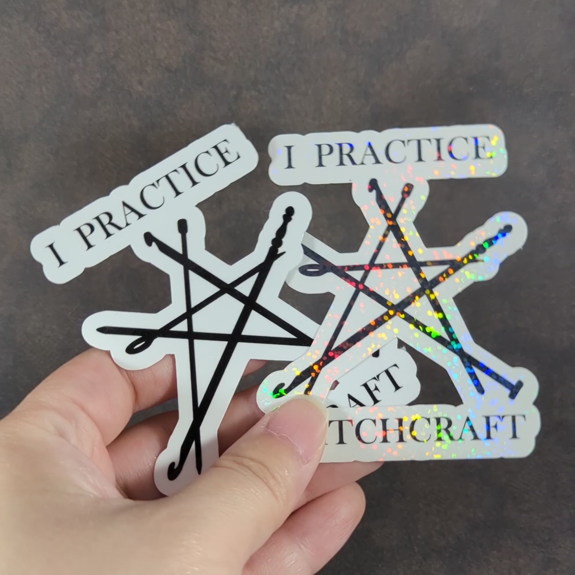 "Video of a pair of 'I Practice Stitchcraft' stickers featuring knitting needles in a pentagram shape, one with holographic sparkle. Perfect for knitting enthusiasts with a sense of humor and love for crafty decor."