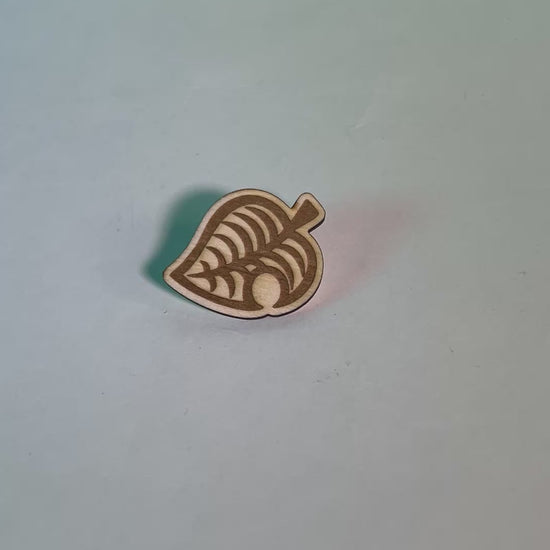 Laser engraved wood pin shaped like the Animal Crossing leaf, perfect gamer gift or accessory for backpacks, jackets, or collectors of gaming-themed items.