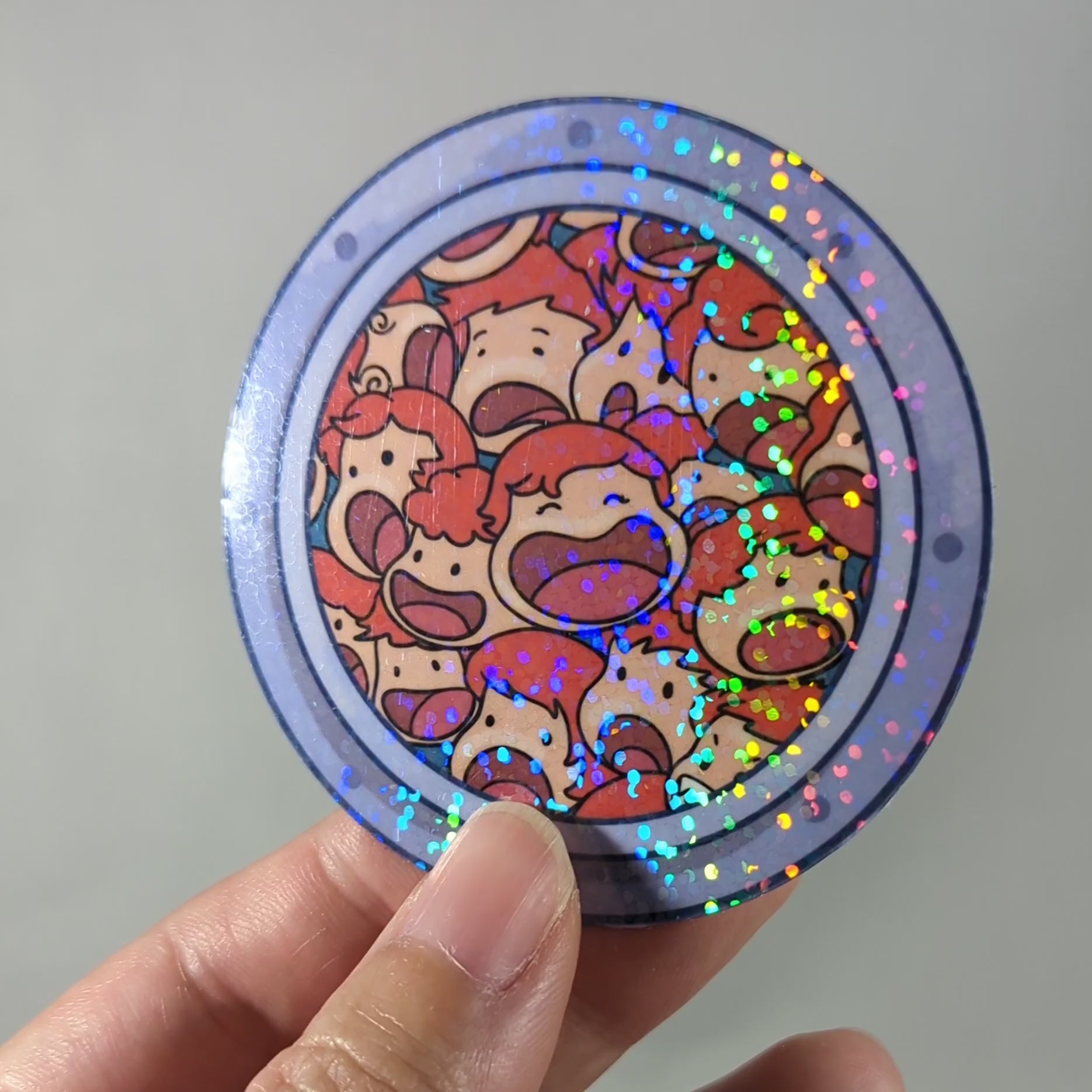 "Video of holographic sticker featuring cute, colorful fish, little sisters from Ponyo, an anime-inspired design in a circular frame. Ideal for fans of whimsical, aquatic-themed art adding sparkle and charm to their decor."